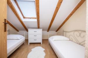 two beds in a attic bedroom with a window at Apartments with parking space Pirovac, Sibenik - 22567 in Pirovac