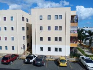 een groot wit gebouw met auto's geparkeerd op een parkeerplaats bij Hermosos apartamentos a 5 mins de la playa Caleta in La Romana