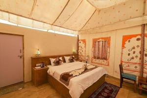 ein Schlafzimmer mit einem Bett und einem Stuhl darin in der Unterkunft Royal Rangers Desert Safari Camp in Jaisalmer