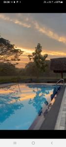 a large swimming pool with a sunset in the background at Sigiriya Elegant Resort in Sigiriya