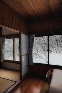 two windows in a room with snow covered trees at Lucky Duck Cabin Myoko in Myoko