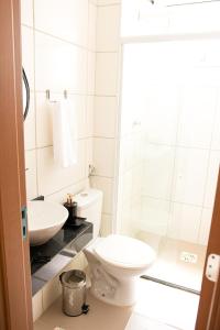 a white bathroom with a toilet and a sink at Apartamento Aconchegante próximo à Arena Castelão in Fortaleza