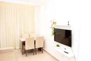 a dining room with a table and a television on a wall at Apartamento Aconchegante próximo à Arena Castelão in Fortaleza