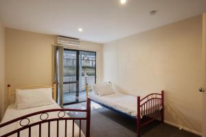 Cette petite chambre comprend 2 lits et une fenêtre. dans l'établissement Relax on Queens - Waikanae Beach Holiday Home, à Waikanae