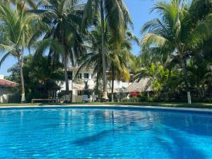 a large swimming pool with palm trees in the background at Villa Grecia-Villas del Pacifico in San José de Guatemala