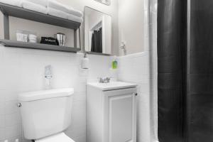 Baño blanco con aseo y lavamanos en Suburban Bliss Getaway Wi-Fi Parking Long Stay en Center Point