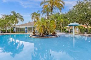 une grande piscine bordée de palmiers et un bâtiment dans l'établissement 4 Bedrooms 3 Bathrooms Lucaya Village 15-101, à Orlando