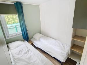 een kleine kamer met 2 bedden en een raam bij Mobil-Home Jullouville, 3 pièces, 4 personnes - FR-1-361A-15 in Jullouville-les-Pins