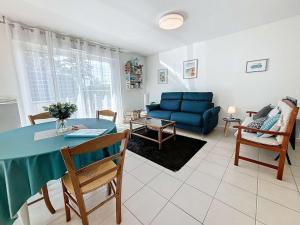 sala de estar con sofá azul y mesa en Appartement Donville-les-Bains, 2 pièces, 2 personnes - FR-1-361-442, en Donville-les-Bains