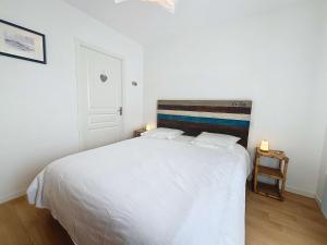 1 dormitorio con 1 cama blanca grande y 2 lámparas en Appartement Donville-les-Bains, 2 pièces, 2 personnes - FR-1-361-442, en Donville-les-Bains