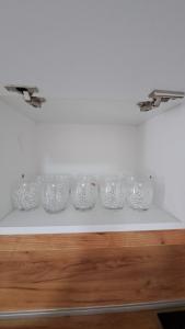 una fila di ciotole di vetro su uno scaffale di Apartman Dzejda a Novi Pazar