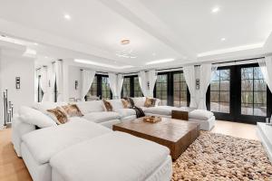 una sala de estar con muebles blancos y ventanas grandes. en Mansion Wifi Fire Pit Sleeps 14 en Dedham