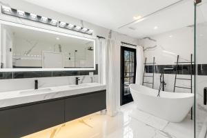 ein weißes Badezimmer mit einer Badewanne und einem großen Spiegel in der Unterkunft Mansion Wifi Fire Pit Sleeps 14 in Dedham