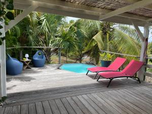 two pink chairs on a deck next to a pool at Charmant bungalow avec petite piscine privée in Rivière-Salée