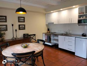 una cocina con mesa y sillas y una cocina con armarios blancos. en The Bruce Waterfront Apartments by AVI, en Akaroa