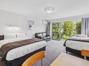 a bedroom with two beds and a couch and a chair at ASURE Brookvale Motel in Wanaka