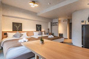 大阪市にあるLite House KuromonⅢのベッド2台とテーブルが備わるホテルルームです。