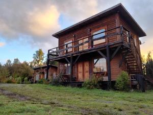 a log cabin with a balcony on a grass field at Rustico Pucon in Pucón