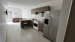 een keuken met een roestvrijstalen koelkast en een bank bij Apartamento condominio alajuela in San Antonio