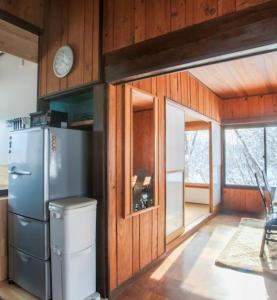 a kitchen with a refrigerator in a room with wooden walls at Lucky Duck Cabin Myoko in Myoko