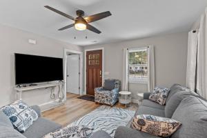 a living room with a couch and a flat screen tv at The Blue Wave Quiet & Cozy Beach Retreat in Oak Island