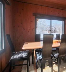 a dining room with a table and chairs and a window at Lucky Duck Cabin Myoko in Myoko