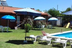 eine Gruppe von Stühlen und Sonnenschirmen neben einem Pool in der Unterkunft Complejo Cantonavi in Mina Clavero