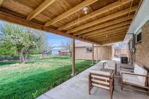 a patio with a wooden pergola and chairs and a yard at Newly Furnished & Updated • 15 min to Denver in Northglenn