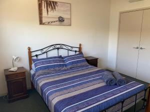 um quarto com uma cama com lençóis listrados em azul e branco em Ningaloo Breeze Villa 3 em Exmouth