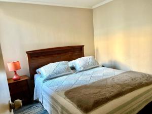 1 dormitorio con 1 cama y 1 lámpara en una mesa en Departamento Temuco Full Equipado en Temuco