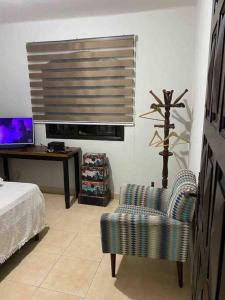 a bedroom with a bed and a chair and a television at Casa 86 Quitandinha Petrópolis in Petrópolis