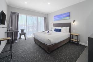 a hotel room with a large bed and a desk at Merewether Motel in Newcastle