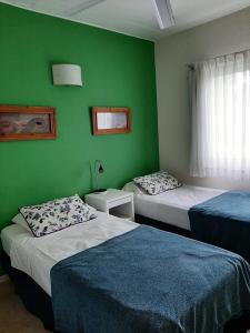 una camera con due letti e una parete verde di Terrazas de Carilo 1C a Carilo