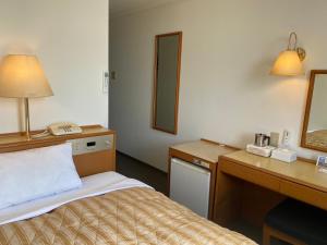 ein Hotelzimmer mit einem Bett, einem Schreibtisch und einem Spiegel in der Unterkunft Hotel Castle Plaza Tagajo in Tagajo + 16 Fotos