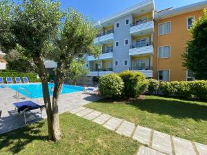 an apartment building with a swimming pool and a tree at Residenza Viel in Bibione