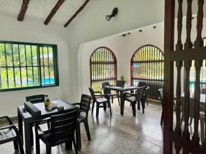 uma sala de jantar com mesas, cadeiras e janelas em Centro Vacacional Campestre La Sabrina em Villeta
