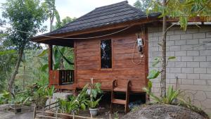 a wooden cabin with a chair and a window at MY HOME tetebatu in Tetebatu