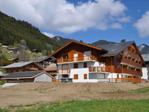 a house on a hill with mountains in the background at Appartement 2 pièces avec balcon sud, parking et cave à La Chapelle-d'Abondance - FR-1-692-99 in La Chapelle-dʼAbondance
