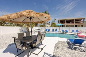 einen Tisch mit einem Strohschirm neben einem Pool in der Unterkunft Oceanview Retreat/Perfect for Groups/Heated Pool in Fort Myers Beach