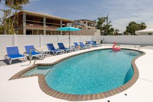 a swimming pool with chairs and an umbrella at Oceanview Retreat/Perfect for Groups/Heated Pool in Fort Myers Beach