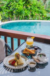 - une table avec deux assiettes de nourriture et une boisson dans l'établissement Giriwood Hotel & Villa, à Munduk