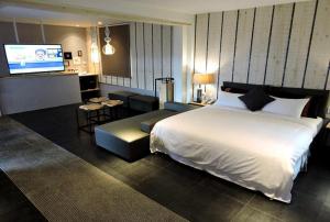 a bedroom with a large white bed and a television at Roppongi Motel - Dalian in Pingtung City