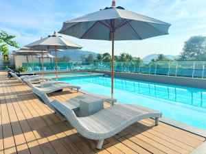 Clarian Hotel Beach Patong في شاطيء باتونغ: مسبح مع كرسيين للصاله ومظله