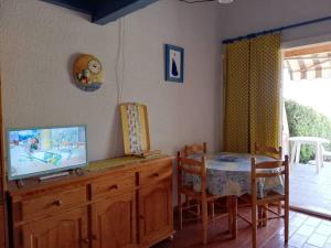 une salle à manger avec une table et une télévision sur une armoire dans l'établissement Maison Le Lavandou, 2 pièces, 4 personnes - FR-1-308-194, au Lavandou