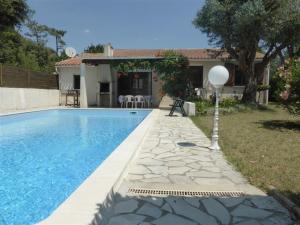 une villa avec une piscine en face d'une maison dans l'établissement Villa La Palmyre, 4 pièces, 7 personnes - FR-1-705-67, aux Mathes