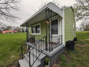 ein kleines grünes Haus mit einer Veranda und einer Treppe in der Unterkunft Sleek and Central Small Home Close to everything in Flint