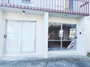 a white house with a balcony and a sliding glass door at 2 bedroom guest suite in North shore in Auckland