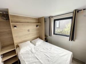 een kleine slaapkamer met een bed en een raam bij Mobil-Home Jullouville, 2 pièces, 2 personnes - FR-1-361A-82 in Jullouville-les-Pins