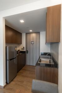 a kitchen with a stainless steel refrigerator and wooden cabinets at The Proud Karon Beach Phuket Trademark Collection By Wyndham in Karon Beach