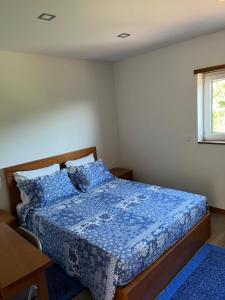 een slaapkamer met een bed met blauwe lakens en een raam bij Casa Alexandre 7 in Monte